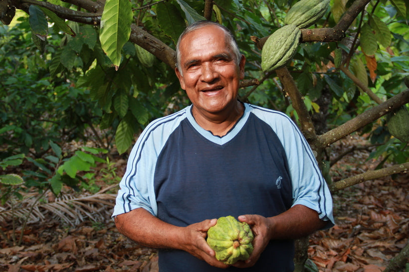 A smiling farmer standing outside of a forest. 